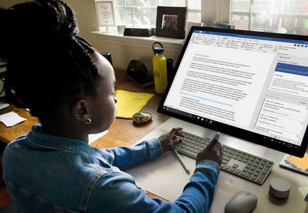 Young person using a wireless keyboard to work on a document in Microsoft Word on a large desktop monitor